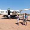 A family with children is waiting near a Cessna 208 B Grand Caravan after arrival at the airstrip
