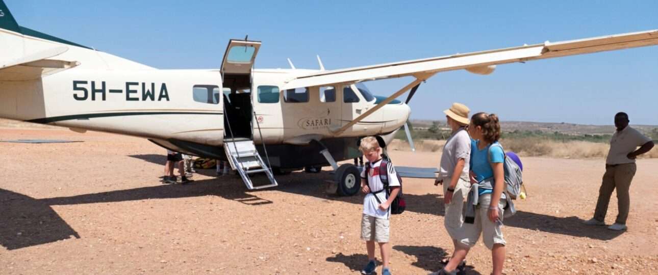 A family with children is waiting near a Cessna 208 B Grand Caravan after arrival at the airstrip